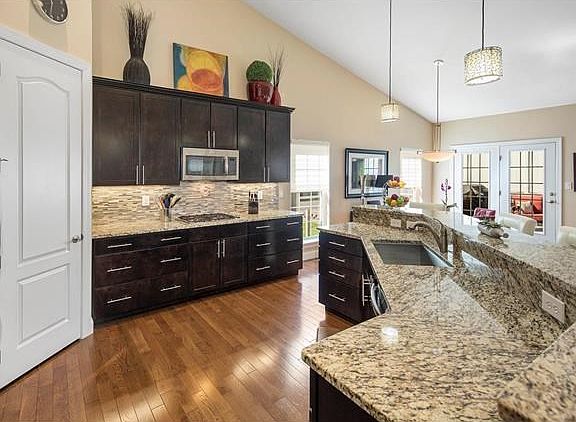 Over sized kitchen has hardwood flooring, granite counter tops, breakfast bar, tile backsplash, under mount sink, gas cooktop, d