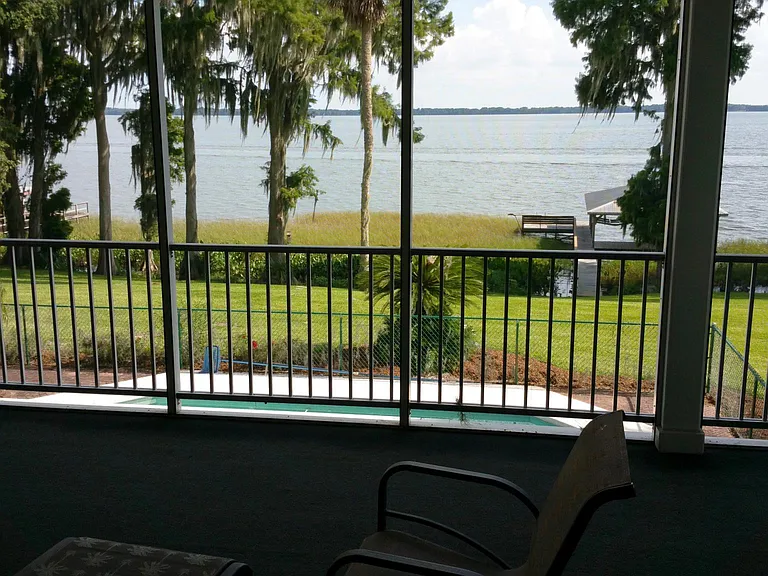 another view from the main screened in porch out to the lake and pool deck. note the flooring has been changed to a beautiful decking.