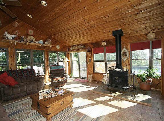 Cedar-lined den with tile floor and wood-burning stove is lined with windows