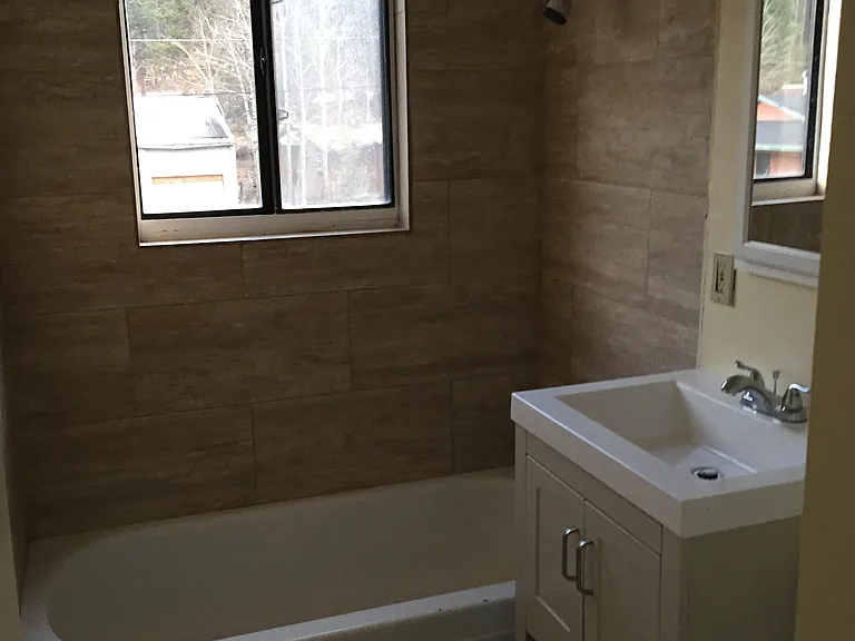 Bathroom with tub is newly remodeled with stylish tube and vanity.