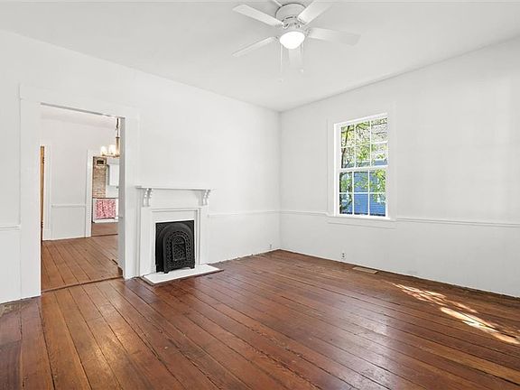 Unfurnished living room with ceiling fan with notable chandelier, dark wood-type flooring, a fireplace, and visible vents