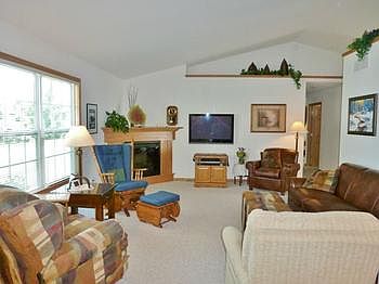 Living room features vaulted ceilings and corner electric fireplace.