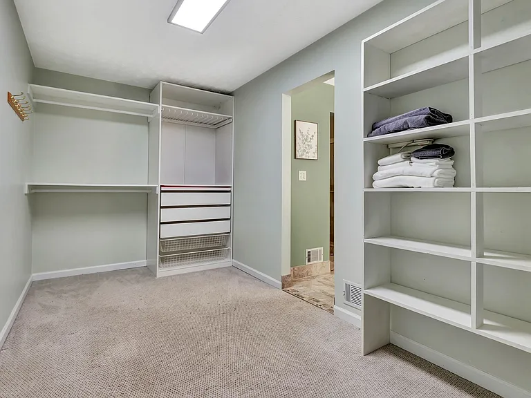 large carpeted walk in closet from the master bathroom