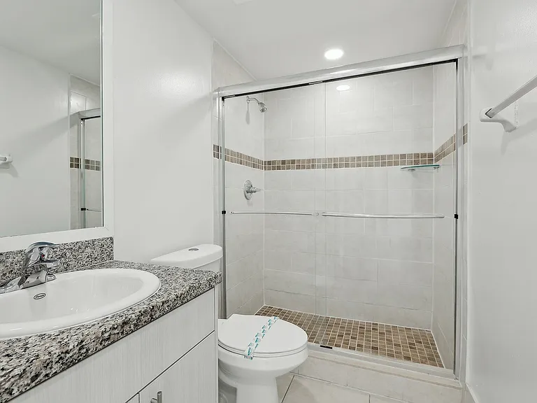 Bathroom featuring a glass-enclosed shower, granite countertop vanity, and elegant tile accents.