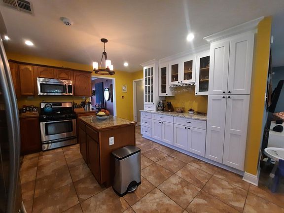 The tiled kitchen has a dishwasher, microwave, gas oven and stove, whirlpool french door refrigerator, and ample storage