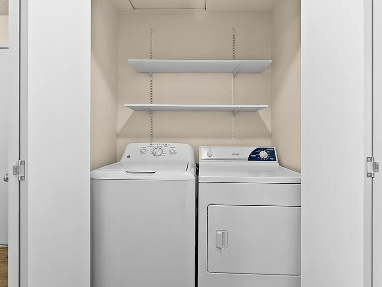 Efficient laundry area with a washer and dryer, complemented by convenient overhead shelving for storage. Efficient laundry area with a washer and dryer, complemented by convenient overhead shelving for storage.