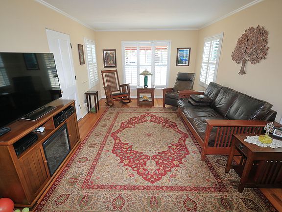 The bright living room has a large picture window and 3 large windows with low e, dual pane glass and plantation shutters, crown and base molding