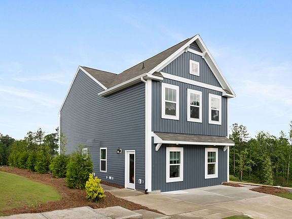 A blue and white house with a lot of windows and a driveway.