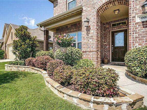Flagstone flowerbed and tree borders enhance the walk to the beautiful leaded glass front door and covered front porch.