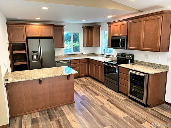 Island kitchen with pull out shelving on the left pantry and under island, finger print proof slate appliances and beverage cooler on the far right