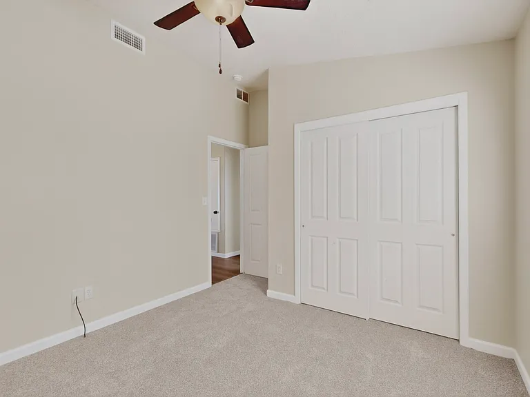 Bedroom #1 features a full closet with bypass doors, a window with blinds for natural light, a ceiling fan for great airflow and the vaulted ceilings for a spacious feel.