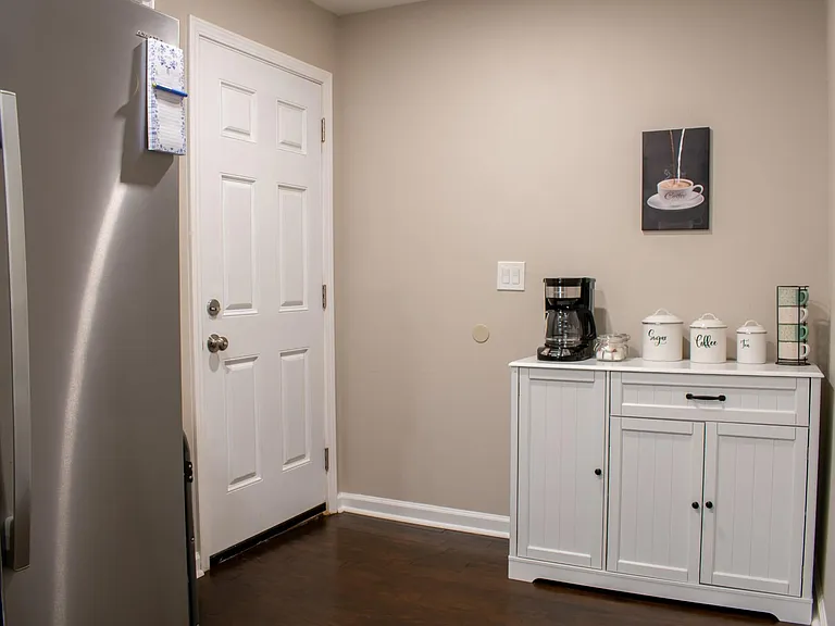 Kitchen nook includes a refrigerator and a dedicated beverage station with extra storage for pantry items and essentials.