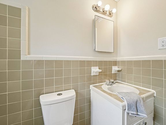 Full size tube, shower, with the charm of original tile, sink, toilet, and medicine cabinet with shelves.