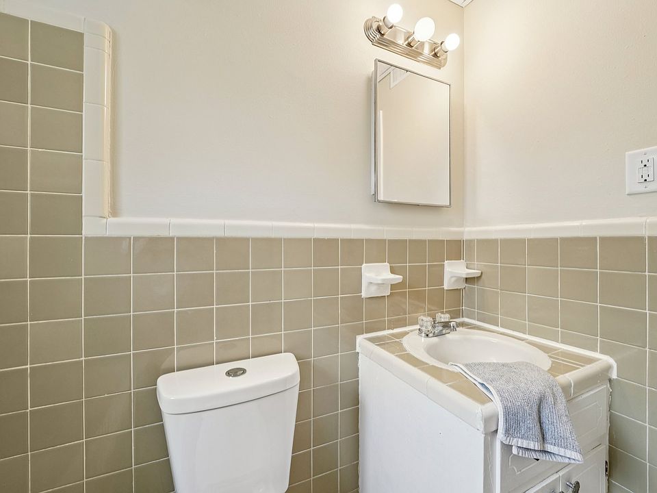 Full size tube, shower, with the charm of original tile, sink, toilet, and medicine cabinet with shelves.