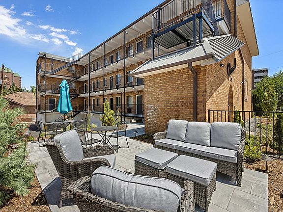 Relax in style on this cozy patio with modern seating and lush greenery.