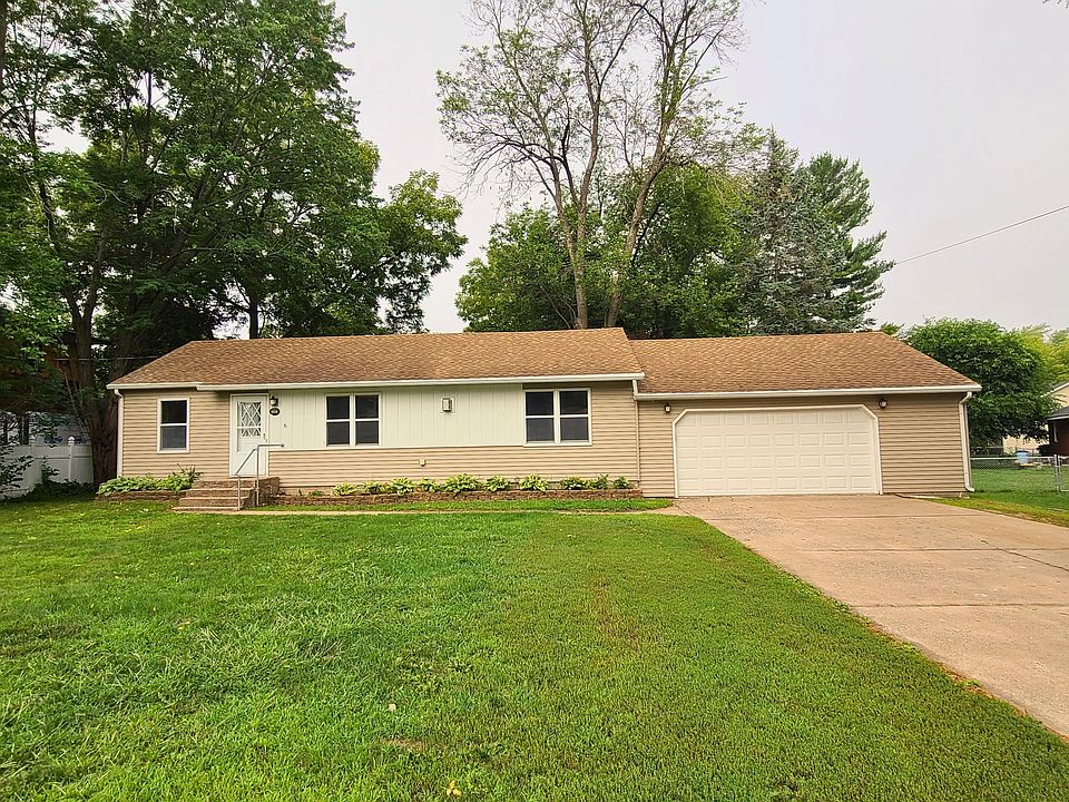Tan and white 3B, 1B rambler with front steps, 2.5 car garage and large front yard