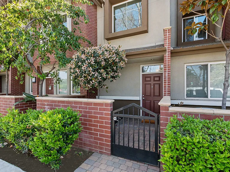 Charming townhouse entrance with lush greenery and brick facade