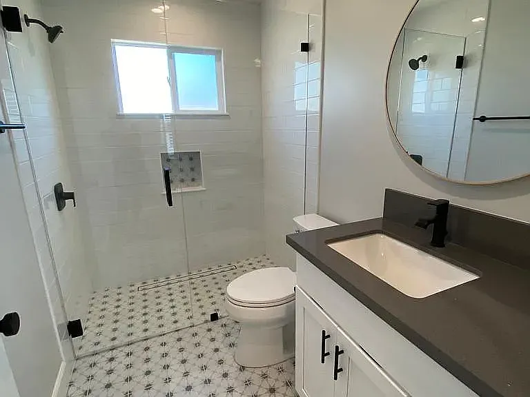 Bath vanity with undermounted sink, quartz counter and shaker cabinets.