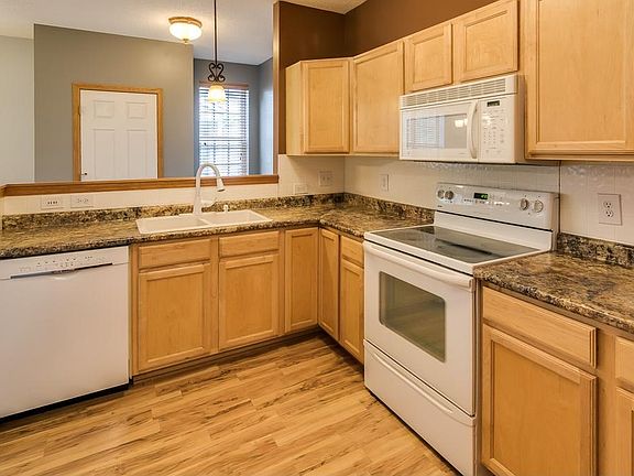 Spacious kitchen has maple cabinetry with coordinating laminate flooring.