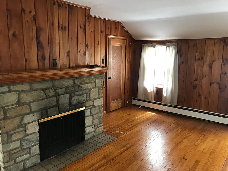 Living area w/ decorative stone fireplace. Door is access to attic.