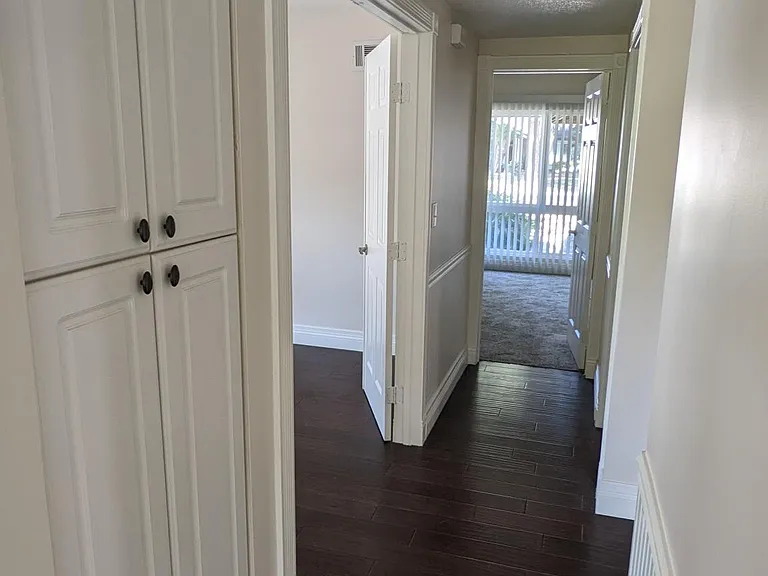 A view down the downstairs hall with the office/den on the left and the half bath on the right and finally the downstairs primary suite. This is floor plan is great for easy access for seniors or people with disabilities. Note that the other two bedrooms