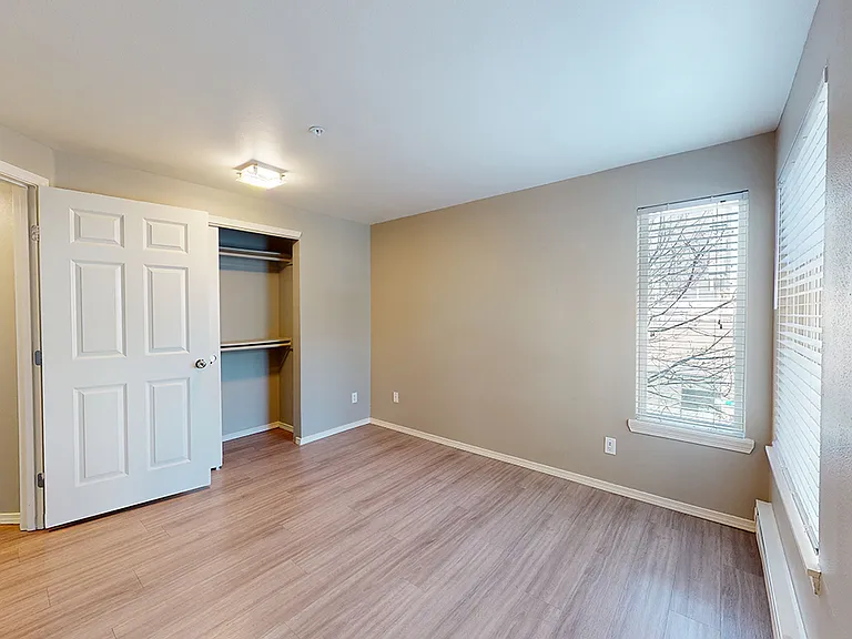 Spacious apartment bedroom with wood-style flooring.