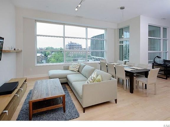 Another view of the spacious living room revealing the door to the balcony and a corner of the dining room being used as a den with 11 foot ceilings, wood floors and large windows.