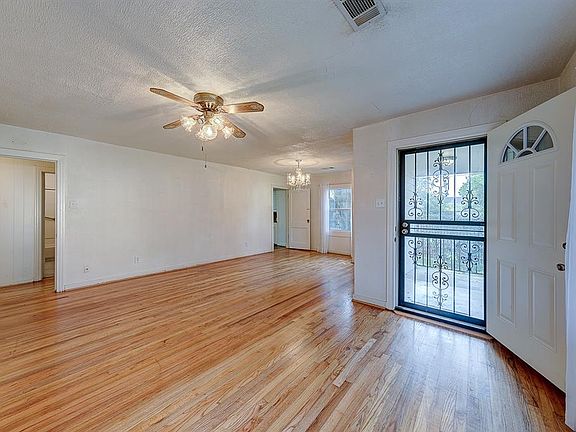 The combined living/dining rooms with the hallway to the left, kitchen door in center frame, and the front door to the right.