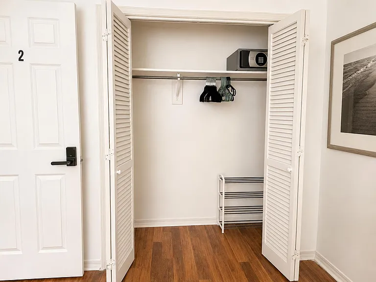 Wide closet with louvered doors, hanging rod and shelf, plus space for shoe or storage organizers.