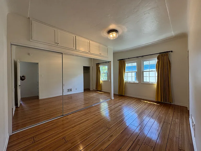 Primary bedroom - mirrored closet doors, overhead storage, 2nd closet on the right, hardwood floors.