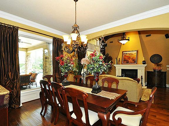 Dining room features wood floors, custom lighting and drapery.