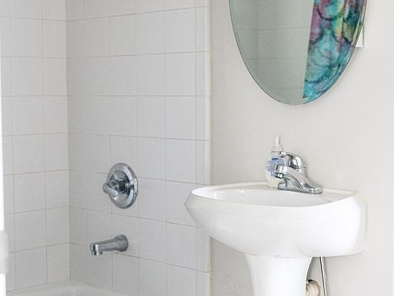 White tiled bathroom shower and tub. Medicine cabinet for storage. The home also has a jacuzzi tub/shower with a total of 2.5 bathrooms.