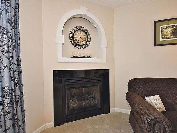 Beautiful corner gas fireplace with logs in living room.