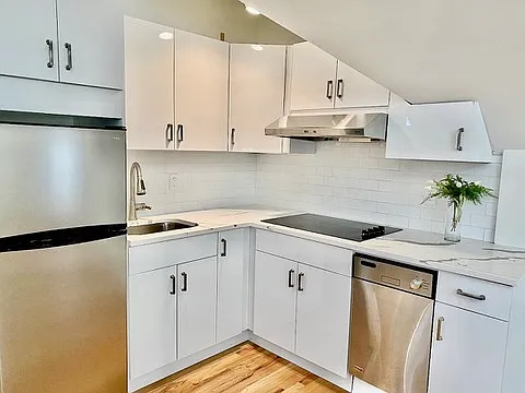A bright kitchen with white cabinetry, subway tile backsplash, and stainless steel appliances.