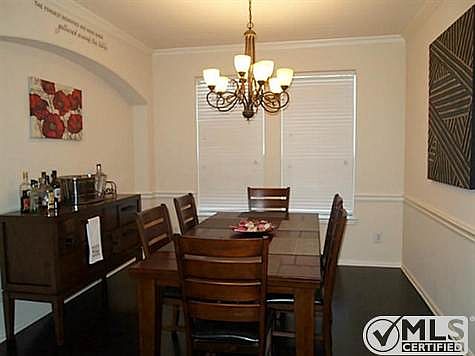 Formal dining room has hardwood flooring, a large chandelier, ch