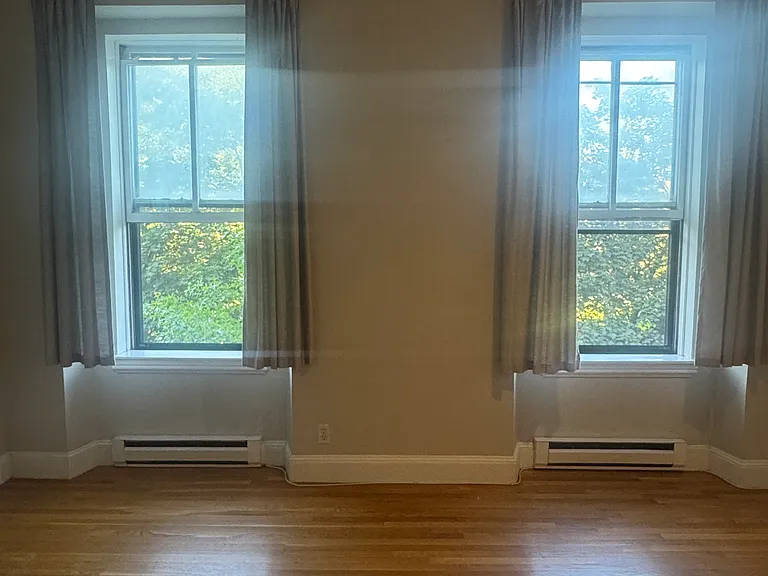 Bright, sun-filled living room with two large windows overlooking Blackstone Square.