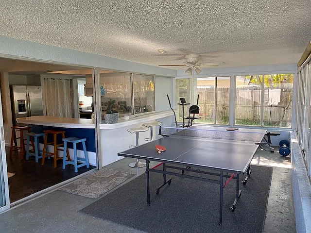 Screen patio with pool table, exercise bike, weight bench, and weights.