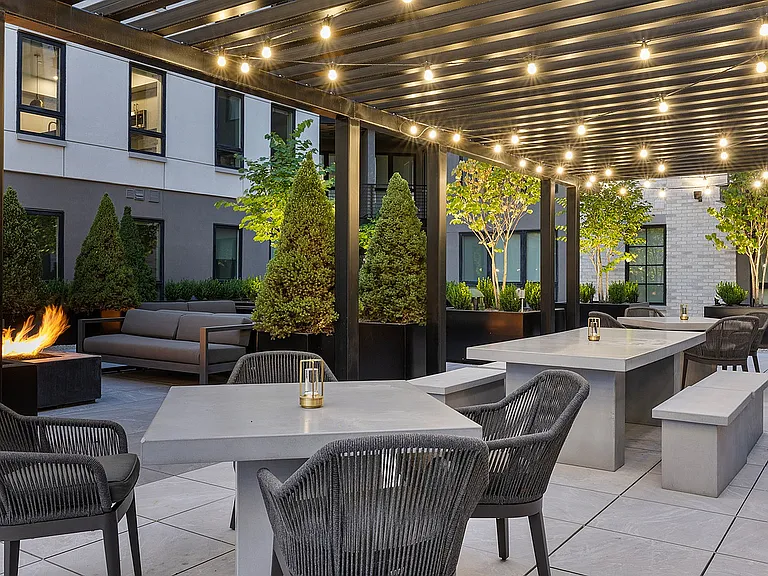 Pergola lounge on rooftop deck lit at dusk