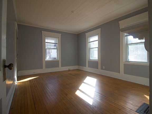 Large bedroom featuring original hardwood floors, crown molding, decorative fireplace, and tin ceiling.