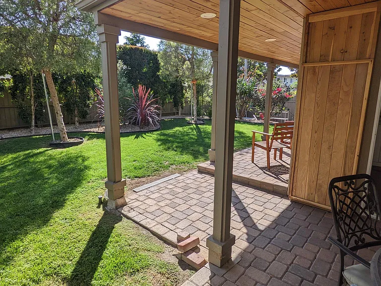 A lush and private backyard with two growing pepper trees
