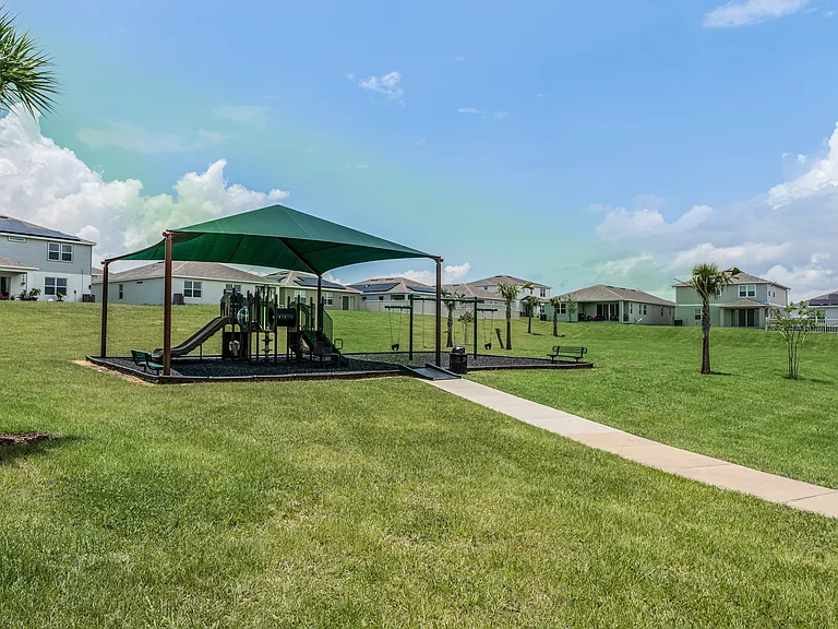 Shaded playground nestled in wide-open green space.