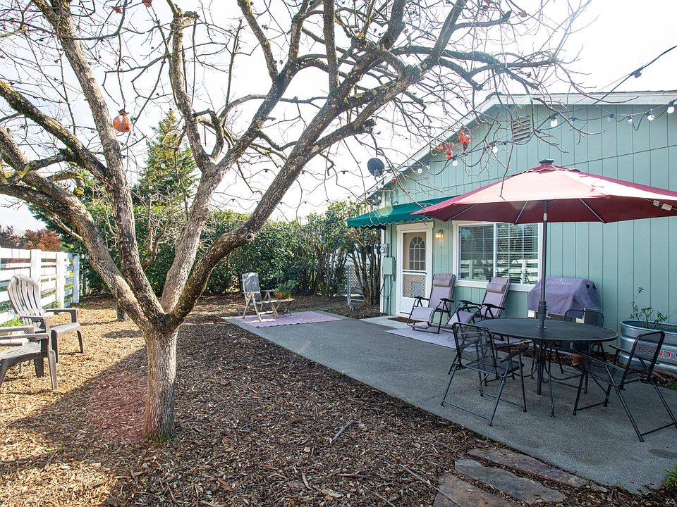 East-facing view of private backyard. Patio furniture includes: Cushioned sectional seating for 6, two large umbrellas, table and four chairs, and full-sized barbeque.