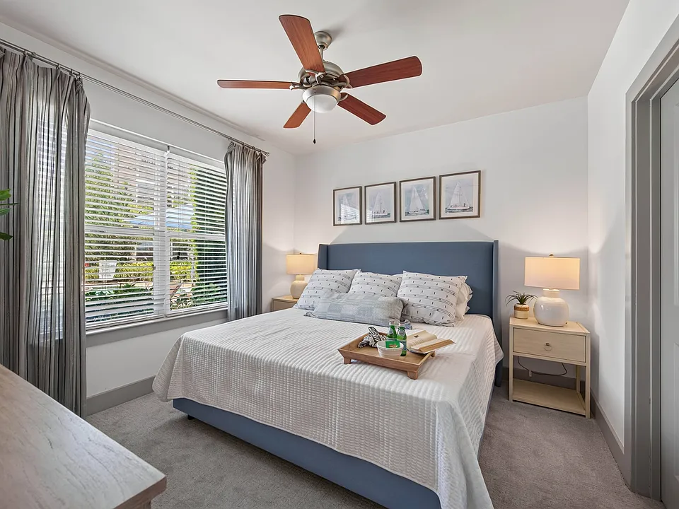 Soft finishes and broad windows give the bedroom a bright, settled feel.