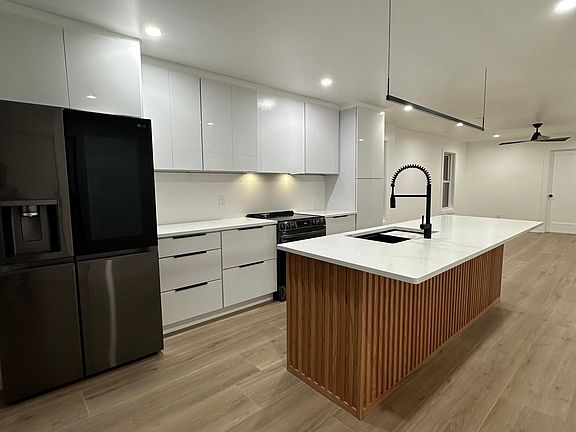 Kitchen with fridge, range, microwave, dishwasher, pantry, and oversized island with room for stools