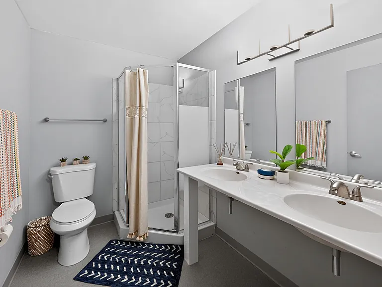 Spacious Bathroom with Dual Sinks and Tiled Shower at University Plaza NIU Apartments