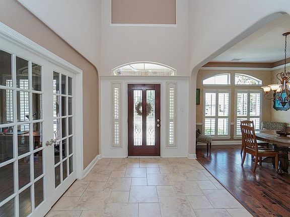 A soaring 2 story foyer featuring deco tile and wood floors and gorgeous Plantation Shutters throughout the home!