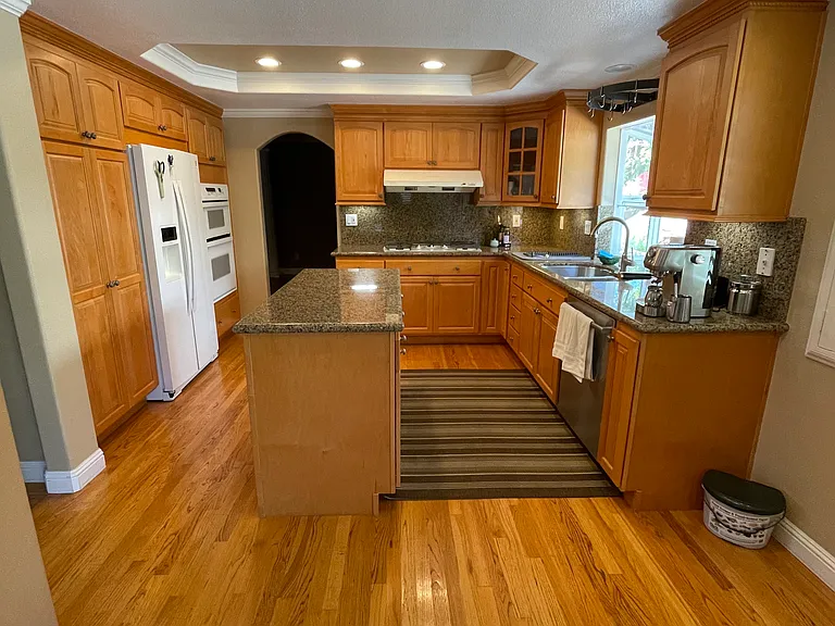Kitchen with granite counter tops and hardwood floor. Refrigerator, built-in oven and microwave, cook top, washer dryer included.