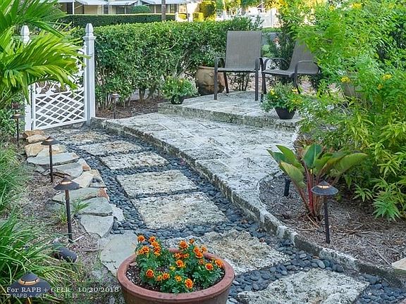 Custom designed gate with a lovely hummingbird opens to coral rock walking path and seating area. Chicago Brick drive and walks 