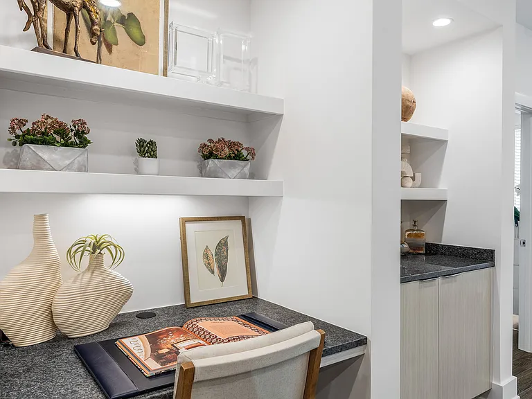 Chic home office nook with elegant decor, featuring modern shelving, lush greenery, and sophisticated artwork.