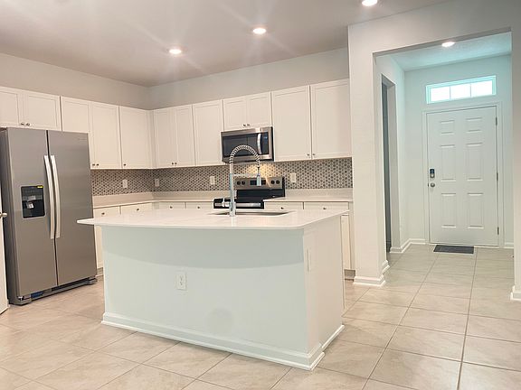 Kitchen with tiled backsplash, stainless appliances, large island and walk in pantry.